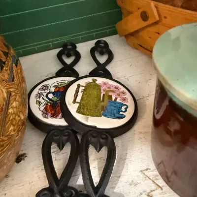 Pair of cast iron tile trivets, coffee pot motif