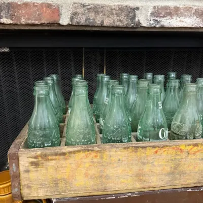 Wooden Coca-Cola crate of vintage green glass bottles