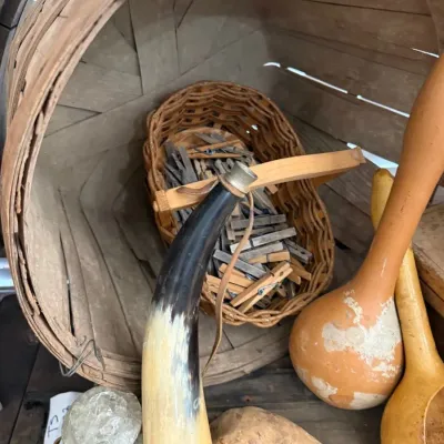 Bushel basket of antique wooden clothespins and powder horn