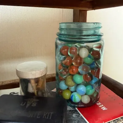 Blue mason jar of vintage marbles with US first aid tin