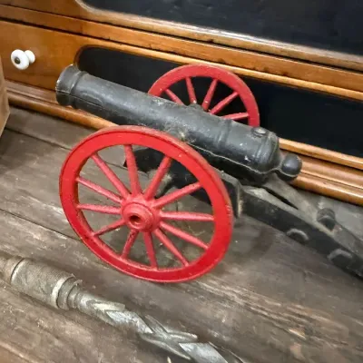 Cast iron toy cannon with red spoke wheels