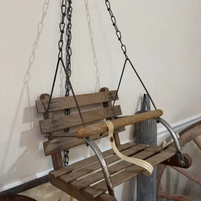 Antique wooden child's porch swing on chains