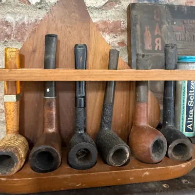 Six estate smoking pipes in wooden rack