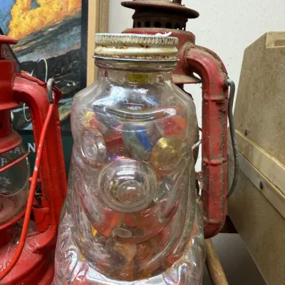 Jar of vintage marbles beside red barn lantern