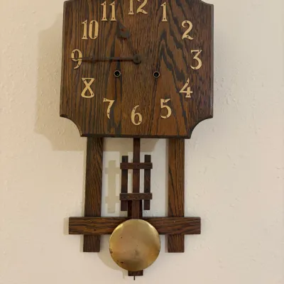 Sale Photo Thumbnail #48: Arts and Crafts style oak wall clock featuring brass numerals, a matching brass pendulum, and a key-wind mechanism.