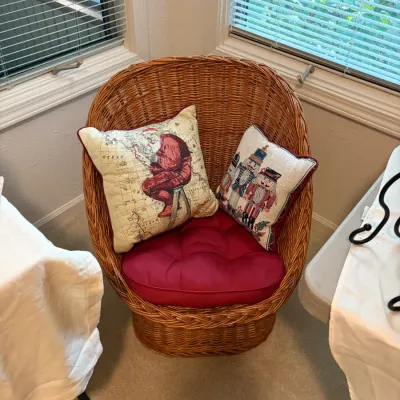 Sale Photo Thumbnail #82: Wicker barrel chair with a rounded back, featuring a red tufted seat cushion and two Christmas-themed throw pillows.