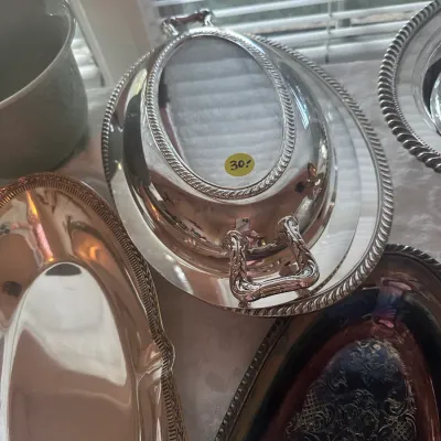 Sale Photo Thumbnail #100: Vintage silver-plated covered entree dish with a rope-twist border and removable handle, displayed alongside other silver-plated serving platters.