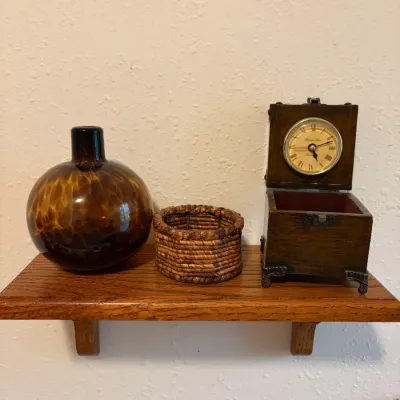 Sale Photo Thumbnail #72: Decorative items displayed on a wooden wall shelf, featuring an amber tortoiseshell glass vase, a small woven basket, and a wooden box clock with a hinged lid.
