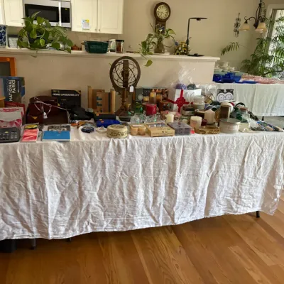 Sale Photo Thumbnail #17: Collection of miscellaneous household goods, office supplies, and decorative items displayed on a table, including candles, notebooks, calendars, and a decorative metal armillary sphere.