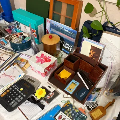 Sale Photo Thumbnail #53: Assortment of office supplies and stationery, including a brown faux-leather desk organizer, calculators, notebooks, calendars, and decorative storage boxes.