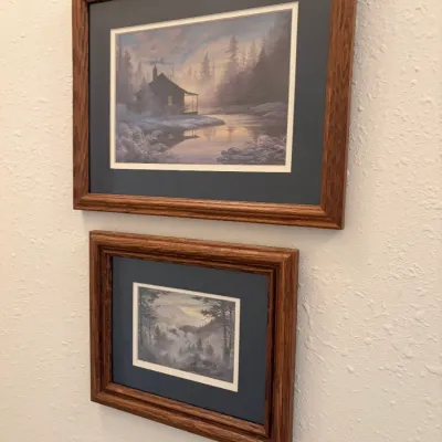 Sale Photo Thumbnail #83: Pair of framed landscape art prints featuring serene nature scenes, presented in matching oak wood frames with dark grey matting.