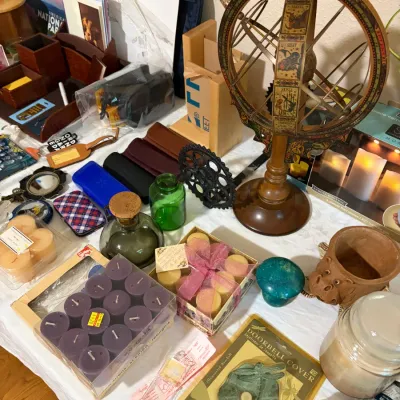 Sale Photo Thumbnail #52: Eclectic collection of home decor items featuring a vintage-style wooden armillary sphere with zodiac illustrations, boxed votive candles, decorative glassware, and a packaged brass dragonfly doorbell cover.