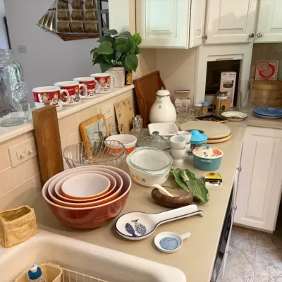 Sale Photo Thumbnail #88: Collection of vintage kitchenware featuring a set of orange and yellow Pyrex nesting bowls, Campbell's Soup mugs, and various ceramic and glass serving dishes.