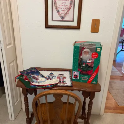 Sale Photo Thumbnail #77: Small wooden writing desk with turned legs and matching Windsor-style chair, displayed with holiday decor including needlepoint stockings and a boxed animated Santa figure.