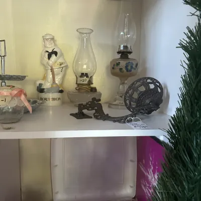 Sale Photo Thumbnail #116: Assortment of vintage collectibles including a ceramic sailor bourbon decanter, two glass oil lamps, and an ornate cast iron wall bracket.
