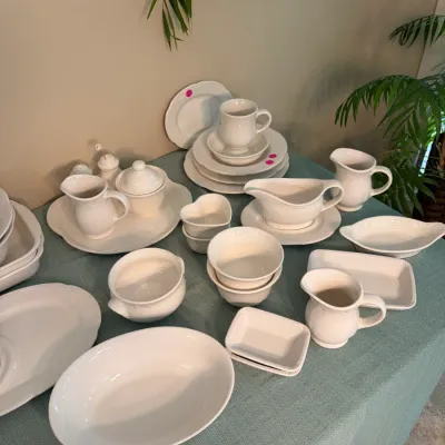 Sale Photo Thumbnail #59: Collection of classic white ceramic tableware and serving pieces, including pitchers, bowls, plates, and a gravy boat, featuring a traditional scalloped design.
