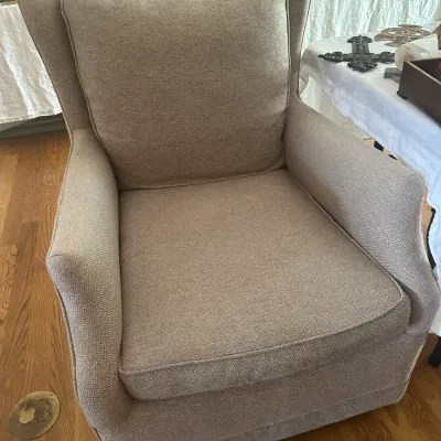 Sale Photo Thumbnail #118: Upholstered wingback swivel rocker in a neutral beige herringbone fabric, featuring a loose seat and back cushion.