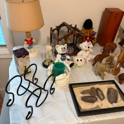 Sale Photo Thumbnail #74: Assortment of home decor and collectibles, featuring a vintage-style boy figurine table lamp, plush toys, small animal figurines, and a framed fossil specimen display.