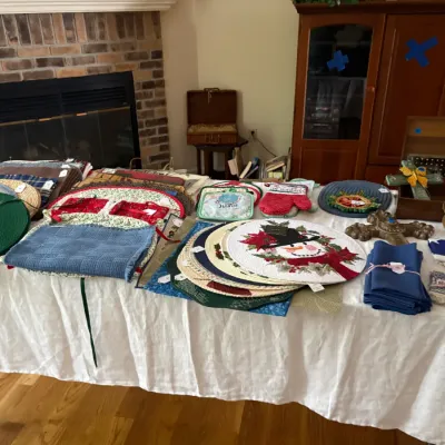 Sale Photo Thumbnail #18: Selection of home textiles and holiday decor, featuring round woven placemats, a snowman-themed placemat, blue cloth napkins, and various kitchen accessories.