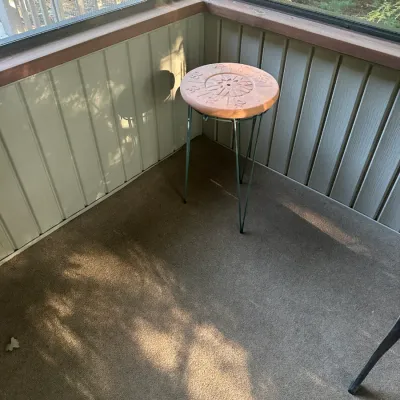 Sale Photo Thumbnail #109: Small round accent table or plant stand featuring a terracotta-colored top with an embossed compass design, supported by green metal hairpin legs.