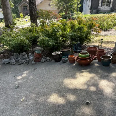 Sale Photo Thumbnail #32: Collection of assorted garden pots, including terracotta and glazed ceramic planters, alongside concrete garden statues of cherubs and animals.