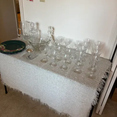 Sale Photo Thumbnail #95: Collection of vintage etched crystal stemware, including wine glasses and coupes, displayed alongside a matching pitcher, decanter, and large serving bowl.