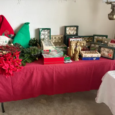 Sale Photo Thumbnail #22: Collection of vintage Christmas decorations, including boxed glass ball ornaments, faux poinsettias, holiday greenery, and gold-colored figurines.