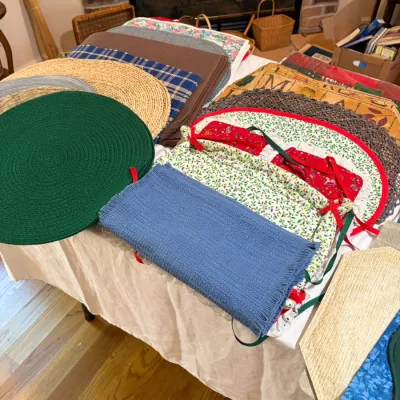 Sale Photo Thumbnail #47: Assortment of vintage and country-style table linens, including braided round placemats, woven straw mats, and festive holiday chair pads with ties.