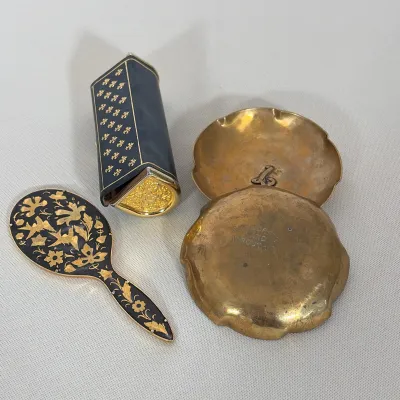 (4pc) GUILDCRAFT HAND WROUGHT BRASS TRAYS, ITALIAN LEATHER LIPSTICK CASE, AND ENAMELED HAND MIRROR
This four-piece vanity set includes a...