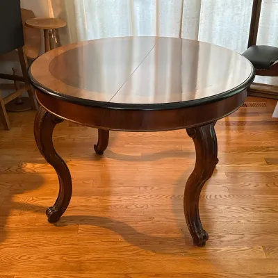 EMPIRE STYLE ROUND DINING TABLE WITH SCROLL FEET
The table features a circular wood top with a two-tone veneer design and a dark-finished...