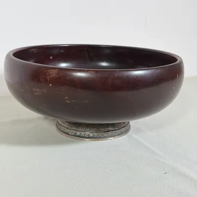 WOODEN SERVING BOWL WITH REPOUSSÉ STERLING SILVER BASE
A deep circular wooden bowl featuring a dark-stained finish and a rounded rim. The...