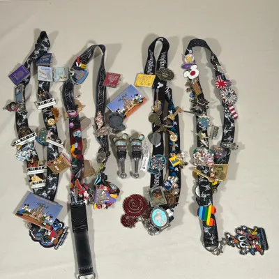 COLLECTION OF DISNEY ENAMEL PINS, LANYARDS, AND BOTTLE STOPPERS
This lot contains four Disney-themed lanyards and over thirty assorted...