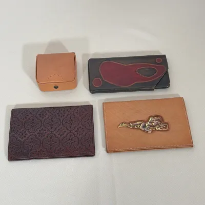 (4pc) LOT OF FOUR VINTAGE ASSORTED LEATHER WALLETS AND JEWELRY CADDY
This lot includes three vintage leather wallets and one structured...