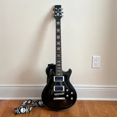 CHARVEL DESOLATION DS-1 ST ELECTRIC GUITAR
Single-cutaway electric guitar featuring a black sparkle finish with abalone binding and...