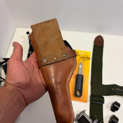 Sale Photo Thumbnail #292: Putter return, leather gun holster, suspenders, knife, sight mounts, hand radio, fishing reel