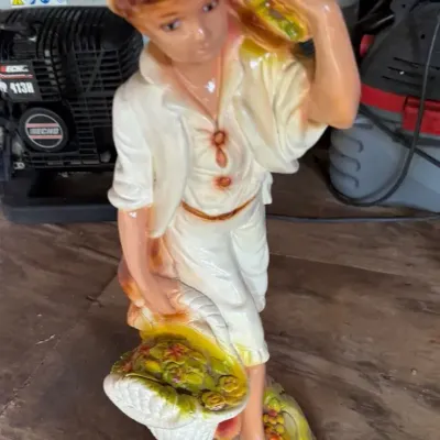Vintage hand-painted ceramic or chalkware statue of a young peasant boy harvesting fruit