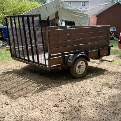 Single-axle open utility trailer equipped with custom wooden sideboards and an A-frame tongue