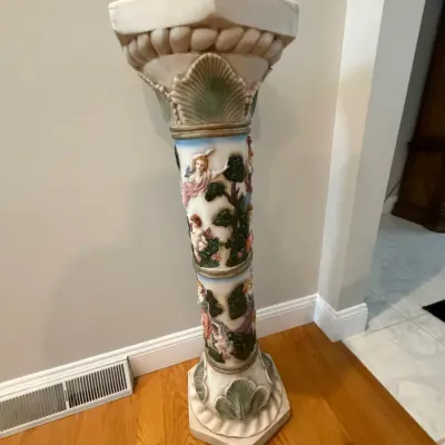 Classical pedestal stand featuring sculpted figurative relief panels with cherubs and acanthus leaf