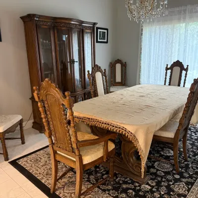 Vintage ornate wooden dining table & chairs featuring a striking carved scroll pedestal base