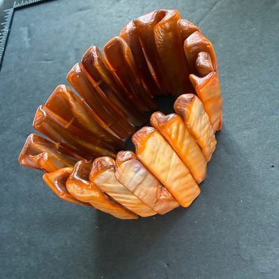 wide stretch cuff bracelet featuring glossy, rectangular shell panels in vibrant orange and amber tones with a natural iridescent sheen