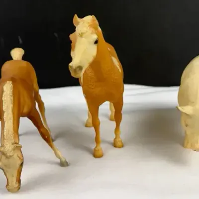 Vintage Breyer Grazing Palomino Foal, a standing palomino horse model, and a farm pig figure