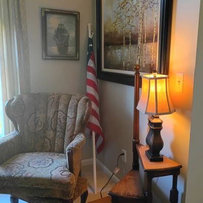 Upholstered wing chair, table lamp, framed art