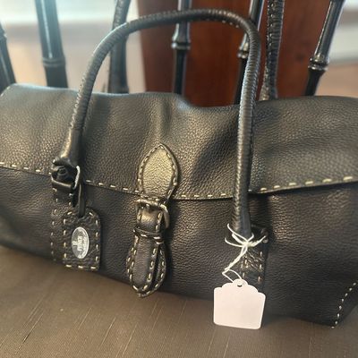 Fendi Selleria black pebbled leather handbag featuring prominent contrast stitching, dual rolled handles, and a central buckle closure.