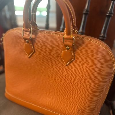 Louis Vuitton Alma handbag in Kenyan Brown Epi leather, featuring structured rolled leather handles and gold-tone hardware.
