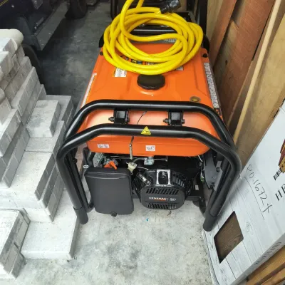 Generac portable generator with an orange housing, black protective frame, and a coiled yellow power cord resting on top.