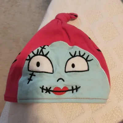 Infant or toddler knot-top beanie featuring the embroidered face of Sally from Disney's The Nightmare Before Christmas.