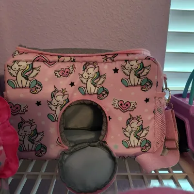 Pink unicorn-patterned small pet carrier bag with a circular zippered opening and shoulder strap.