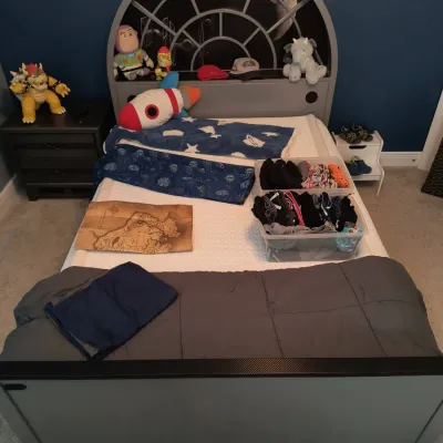 Star Wars Death Star themed twin bed frame with an arched headboard, shown with various toys and bedding.