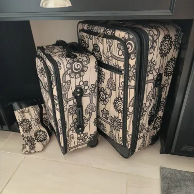 Three-piece American Tourister luggage set featuring a black and white floral pattern, including a large rolling suitcase, a medium...