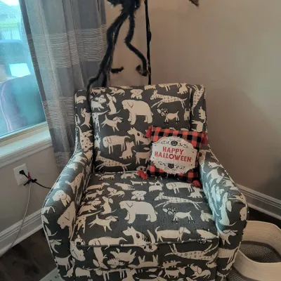 Contemporary upholstered armchair featuring a whimsical grey and white animal print, styled with a red and black plaid "Happy...